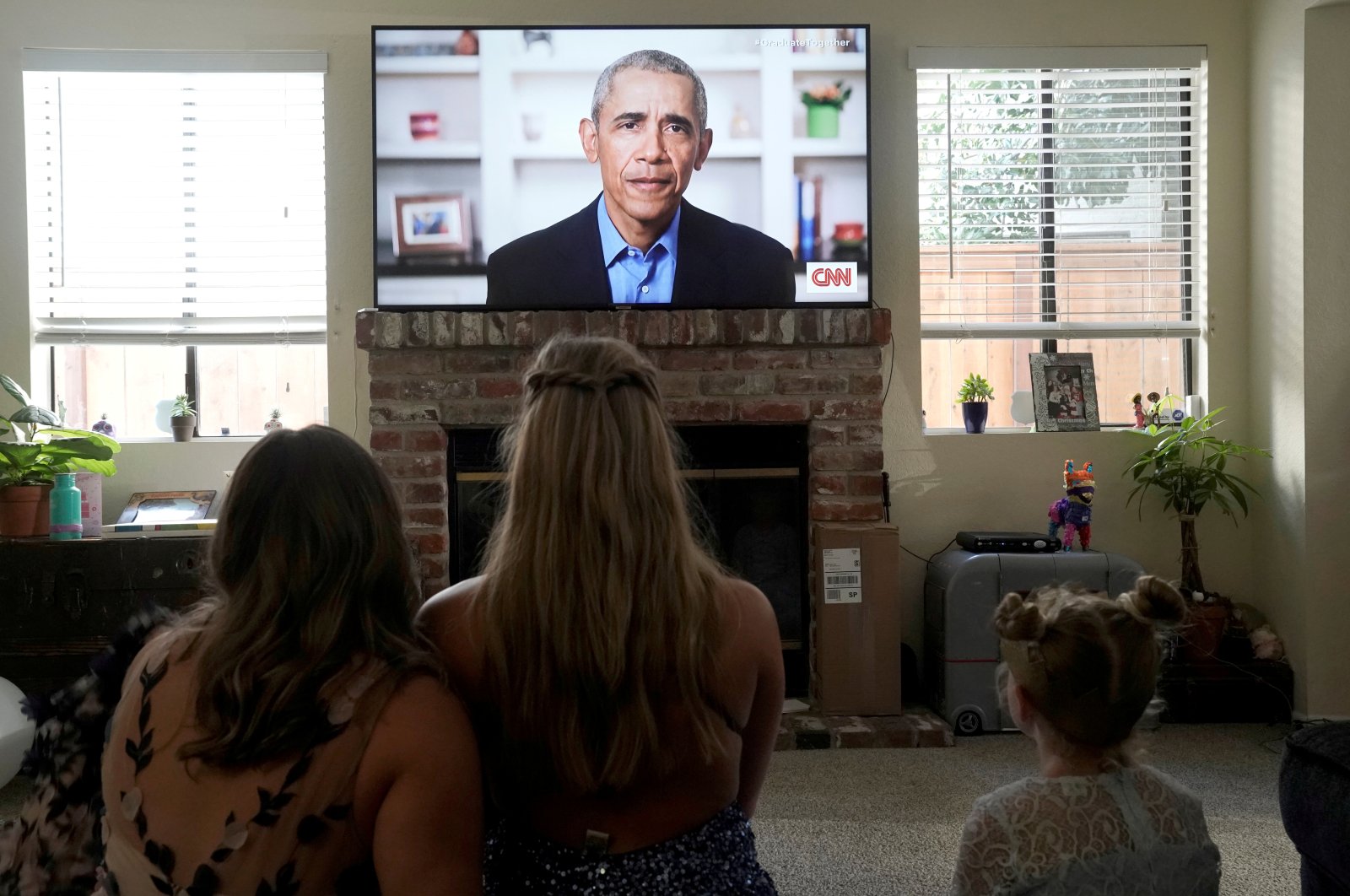 Torrey Pines High School graduating student Phoebe Seip (C), 18, and her sisters Sydney (L), 22, and Paisley, 6, watch former U.S. President Barack Obama deliver a virtual commencement address to millions of high school seniors who will miss graduation ceremonies due to the COVID-19 outbreak, while celebrating Phoebe's canceled prom night at home in San Diego, California, U.S., May 16, 2020. (Reuters Photo)