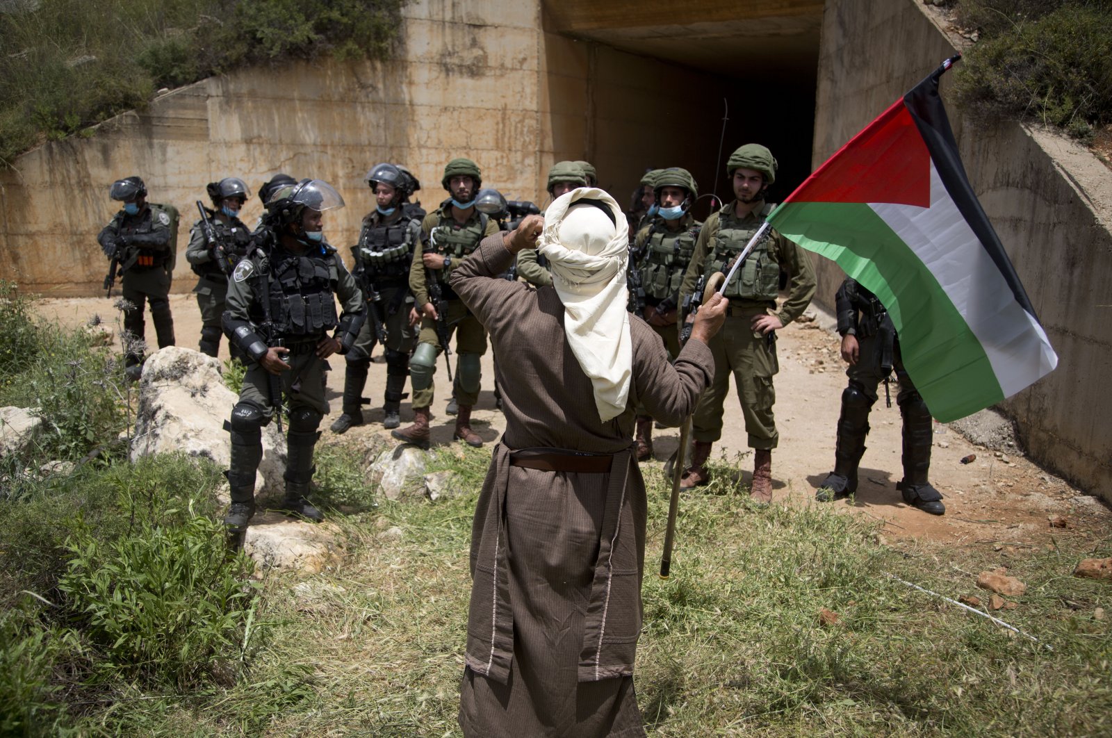 Palestinian holds national flag in fron of Israeli border police during a protest marking the 72nd anniversary "nakba," or catastrophe, near the West Bank city of Nablus, May 15, 2020. (AP)