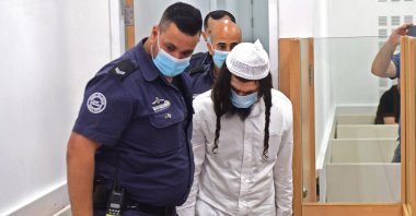 Amiram Ben-Uliel, a Jewish settler, is lead by police into court at the Central Lod District Court, in the central Israeli city on May 18, 2020, for his sentencing hearing over the 2015 arson attack that killed a Palestinian toddler and his parents. (AFP Photo)