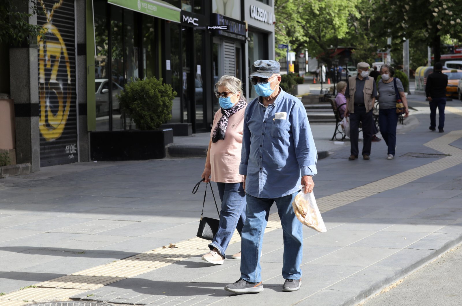 People wearing face masks for protection against coronavirus, walk in popular Tunali Hilmi Street during a four-day curfew declared by the government in an attempt to control the spread of coronavirus, in Ankara, Turkey, Sunday, May 17, 2020. (AP Photo)