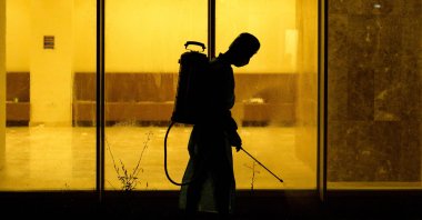 A medical staffer wearing full PPE performs sterilization at the entrance of an isolated section for COVID-19 treatment at a hotel in the sports city of Iraq's southern city of Basra on May 11, 2020. (AFP Photo)