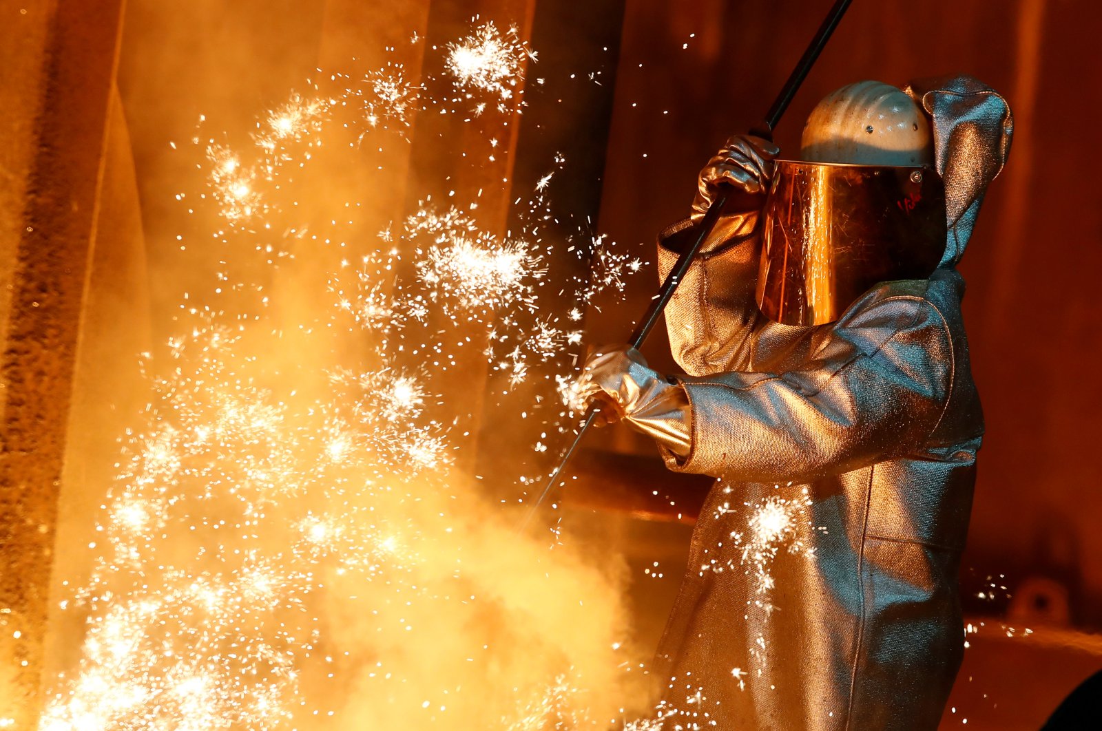 A steel worker of ThyssenKrupp stands amid sparks of raw iron coming from a blast furnace at a ThyssenKrupp steel factory in Duisburg, western Germany, Jan. 30, 2020. (Reuters Photo)