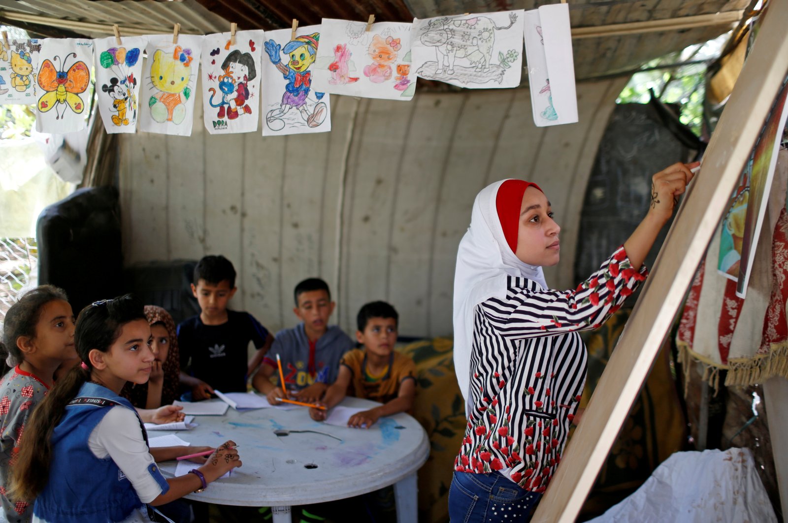 A Palestinian schoolgirl Fajr Hmaid, 13, holds Arabic language lessons for her neighbors' children as schools are shut due to the coronavirus restrictions, at her family house, Gaza, May 19, 2020.