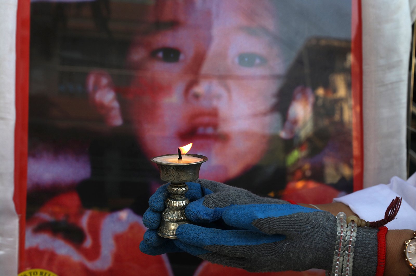 A Tibetan woman living in exile and a member of the Tibetan Women's Association lights a butter lamp during an event to mark the 31st birthday of Panchen Lama in McLeod Ganj, near Dharamsala, India, April 25, 2020.(EPA Photo)