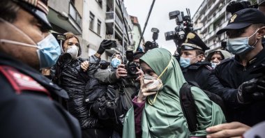 Silvia Romano, escorted by Carabinieri officers, arrives at her home wearing a green garment typical of Somali Muslim women and a surgical mask to guard against COVID-19, in Milan, Italy, May 11, 2020. (AP Photo)