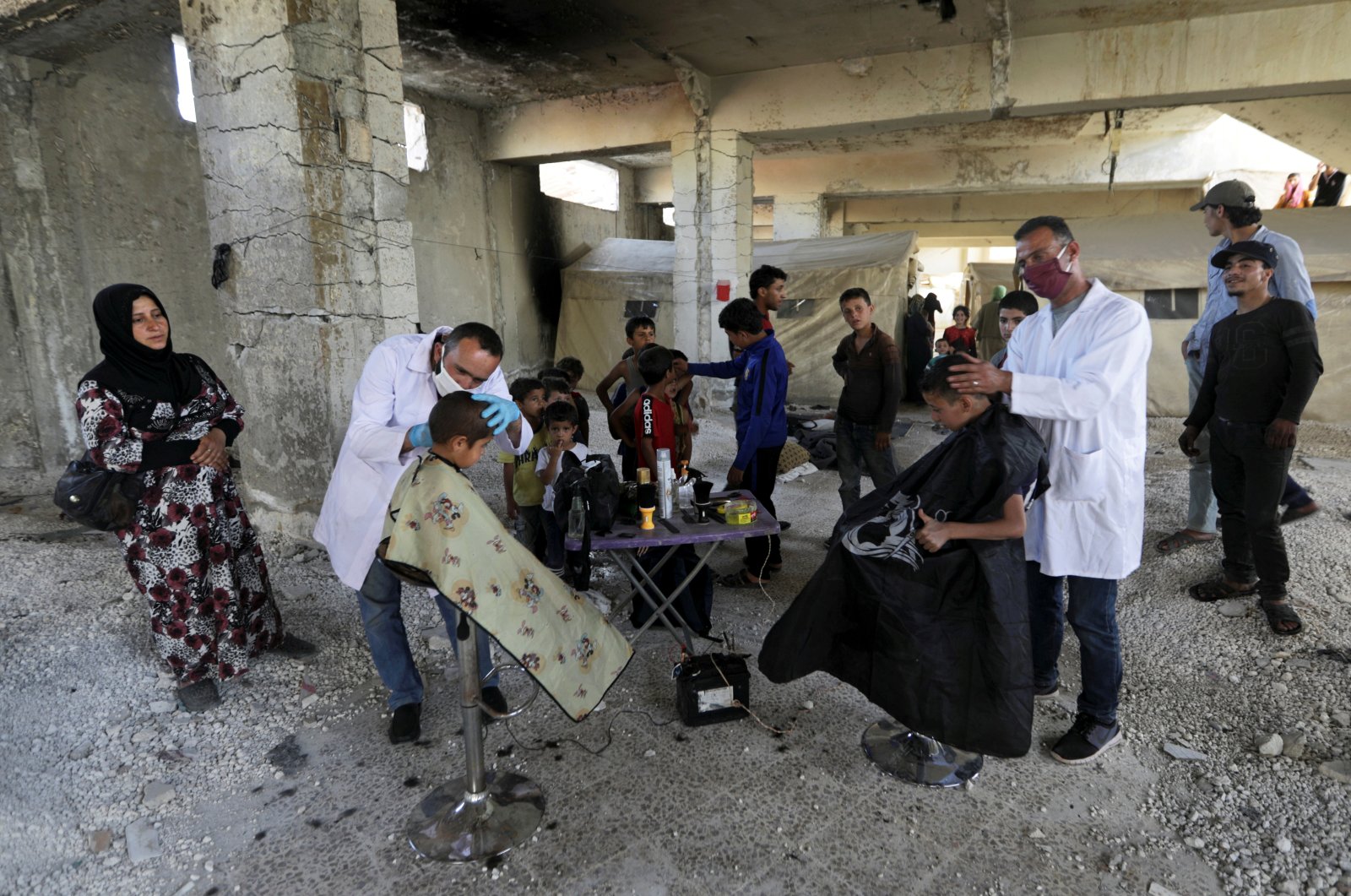 Volunteer hairdressers from the International Association for Relief and Development (ONSUR) wearing face masks and gloves cut the hair of internally displaced children at a camp for the displaced in Idlib, Syria, May 19, 2020. (Reuters Photo)