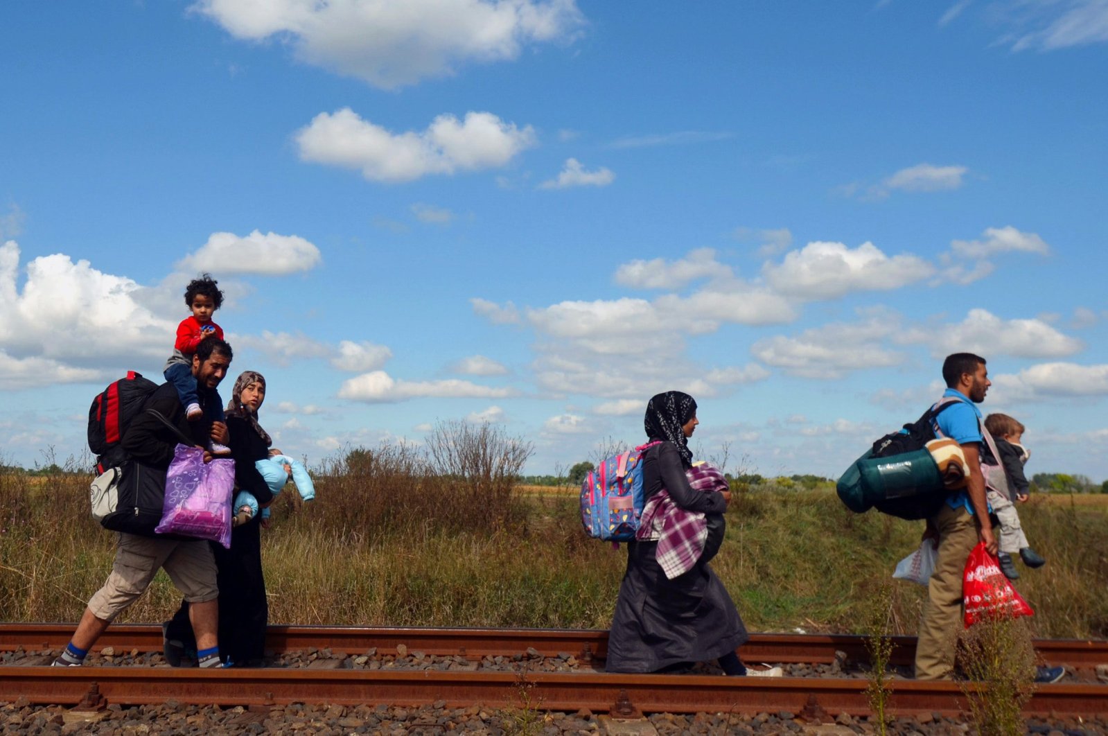 Migrant families walk on the railway track at the Hungarian-Serbian border near the village of Roszke, Hungary, Sept. 6, 2015. (AFP Photo)