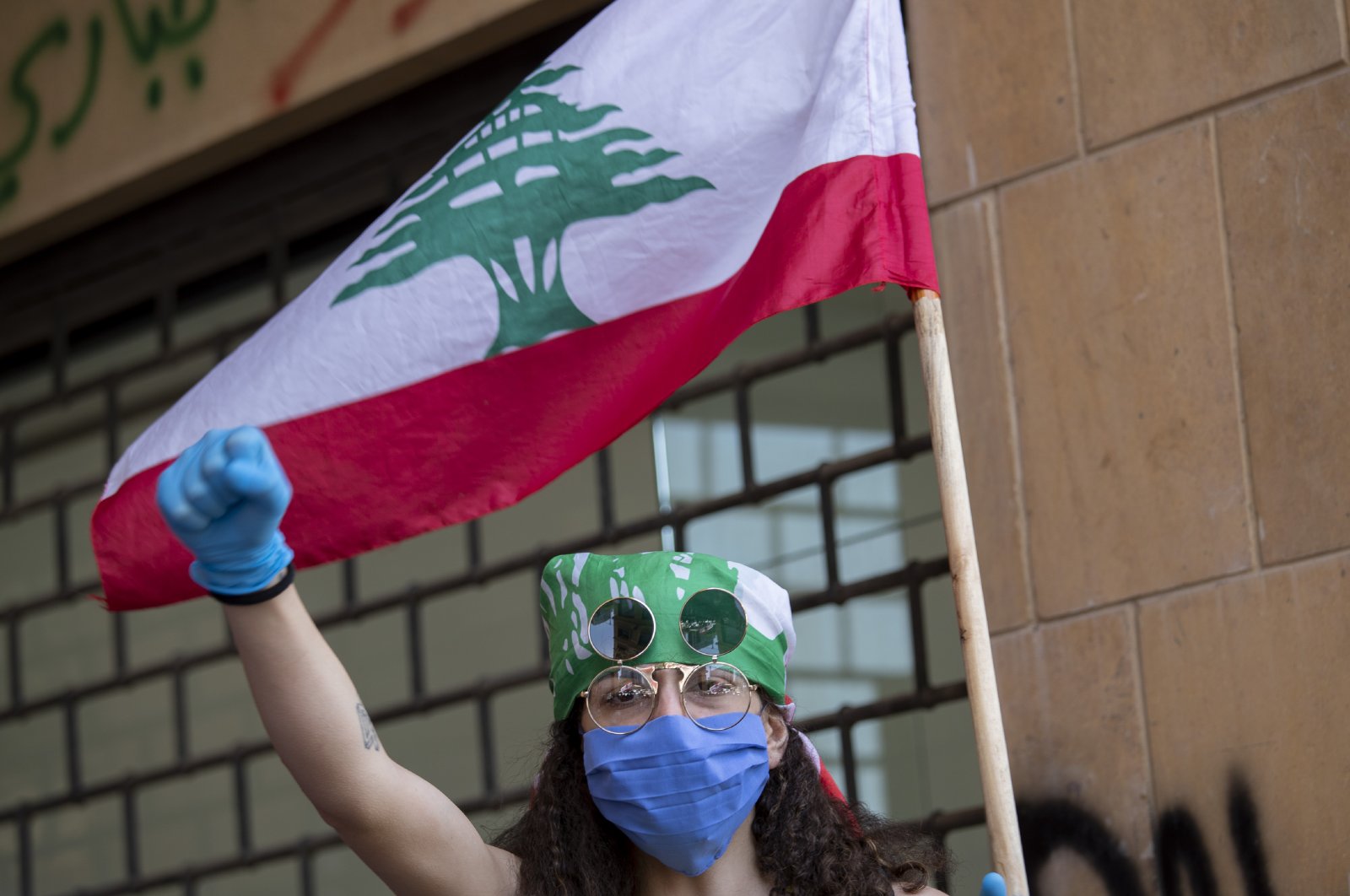 An anti-government protester shouts slogans, while wearing a mask to help curb the spread of the coronavirus, during ongoing protests in front of the Ministry of Economy, in downtown Beirut, Lebanon, May 18, 2020. (AP Photo)