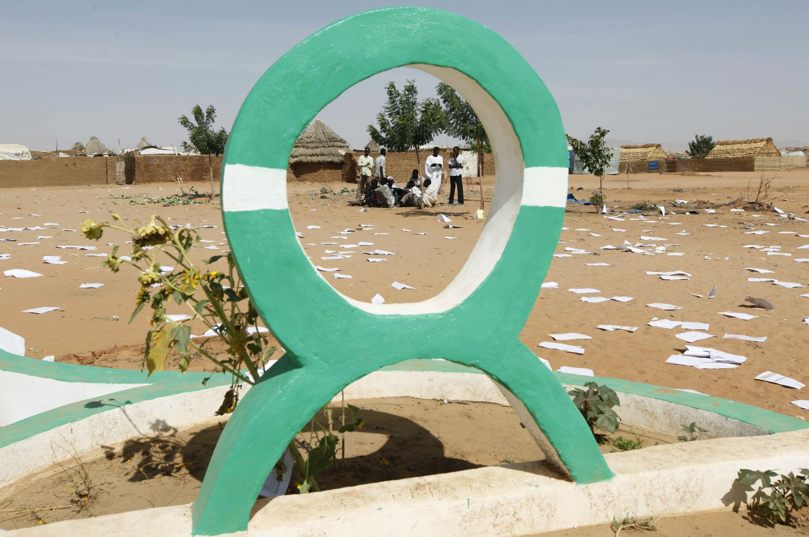Sudanese refugees gather behind the Oxfam logo at al-Salam refugee camp, outside the Darfur town of al-Fasher, March 21, 2009. (AP Photo)