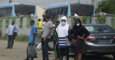 People wearing face masks to protect against the coronavirus wait for a commercial bus, Lagos, May 20, 2020. (AP Photo)