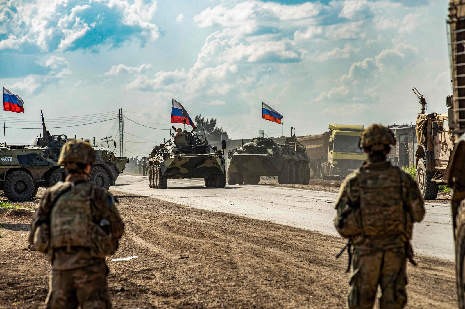 U.S. soldiers stand along a road across from Russian military armored personnel carriers (APCs), near the village of Tannuriyah, east of Qamishli, Syria, May 2, 2020. (AFP Photo)