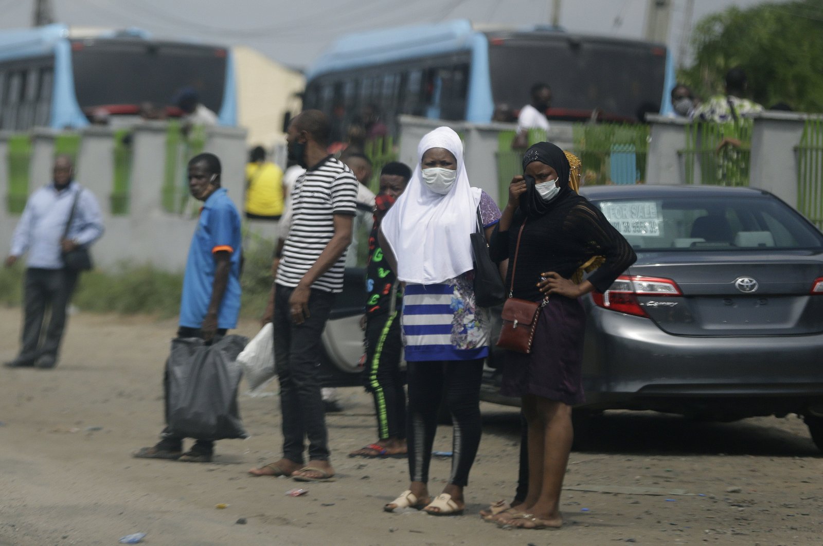 People wearing face masks to protect against the coronavirus wait for a commercial bus, Lagos, May 20, 2020. (AP Photo)
