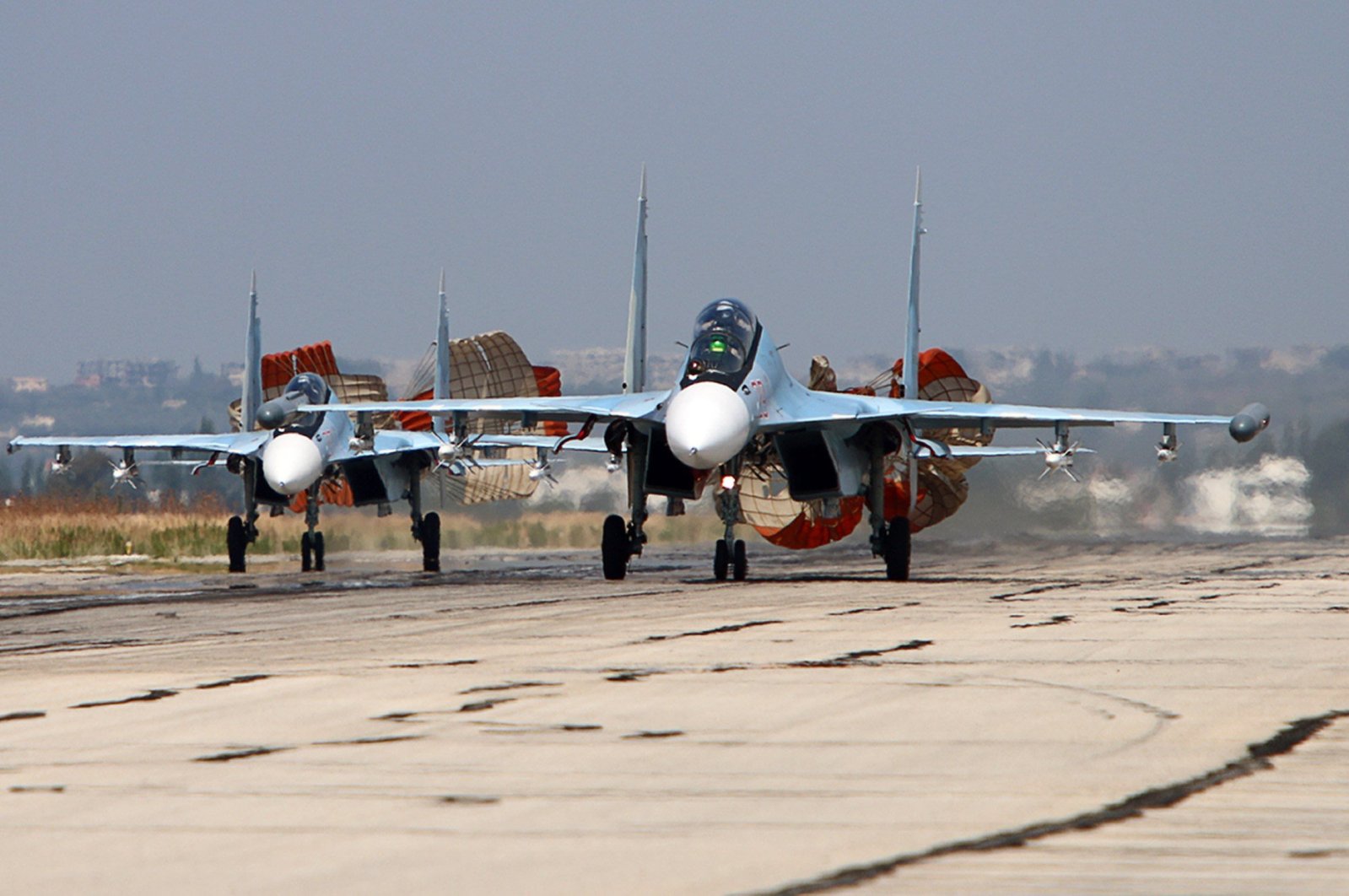 A picture taken on October 3, 2015 shows Russian Sukhoi SU-30 SM jet fighters landing on a runway at the Hmeimim airbase in the Syrian province of Latakia. (AFP Photo)
