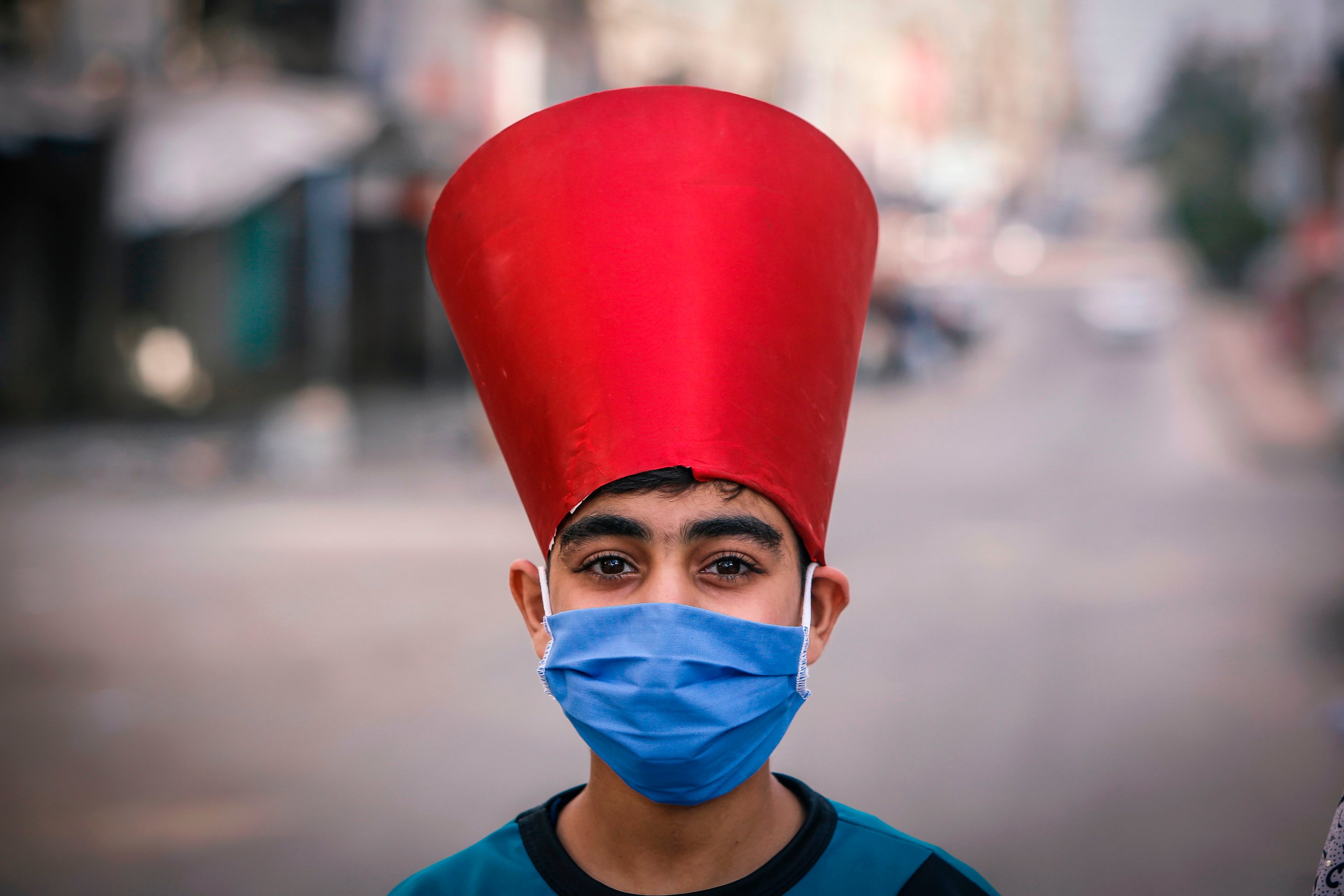 A Palestinian child wearing a paper hat and a mask due to the coronavirus pandemic walks along a street after performing prayers on the first day of Eid al-Fitr, Gaza City, May 24, 2020. (AFP Photo)