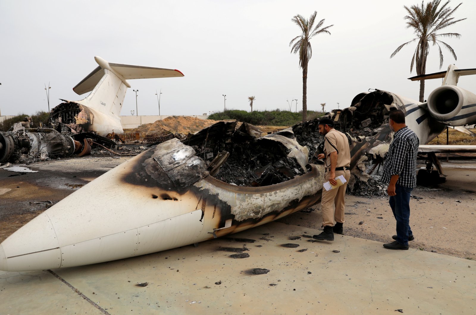 A policeman and a man inspect a passenger plane damaged by shelling at Mitiga airport in Tripoli, Libya, May 10, 2020. (Reuters Photo)