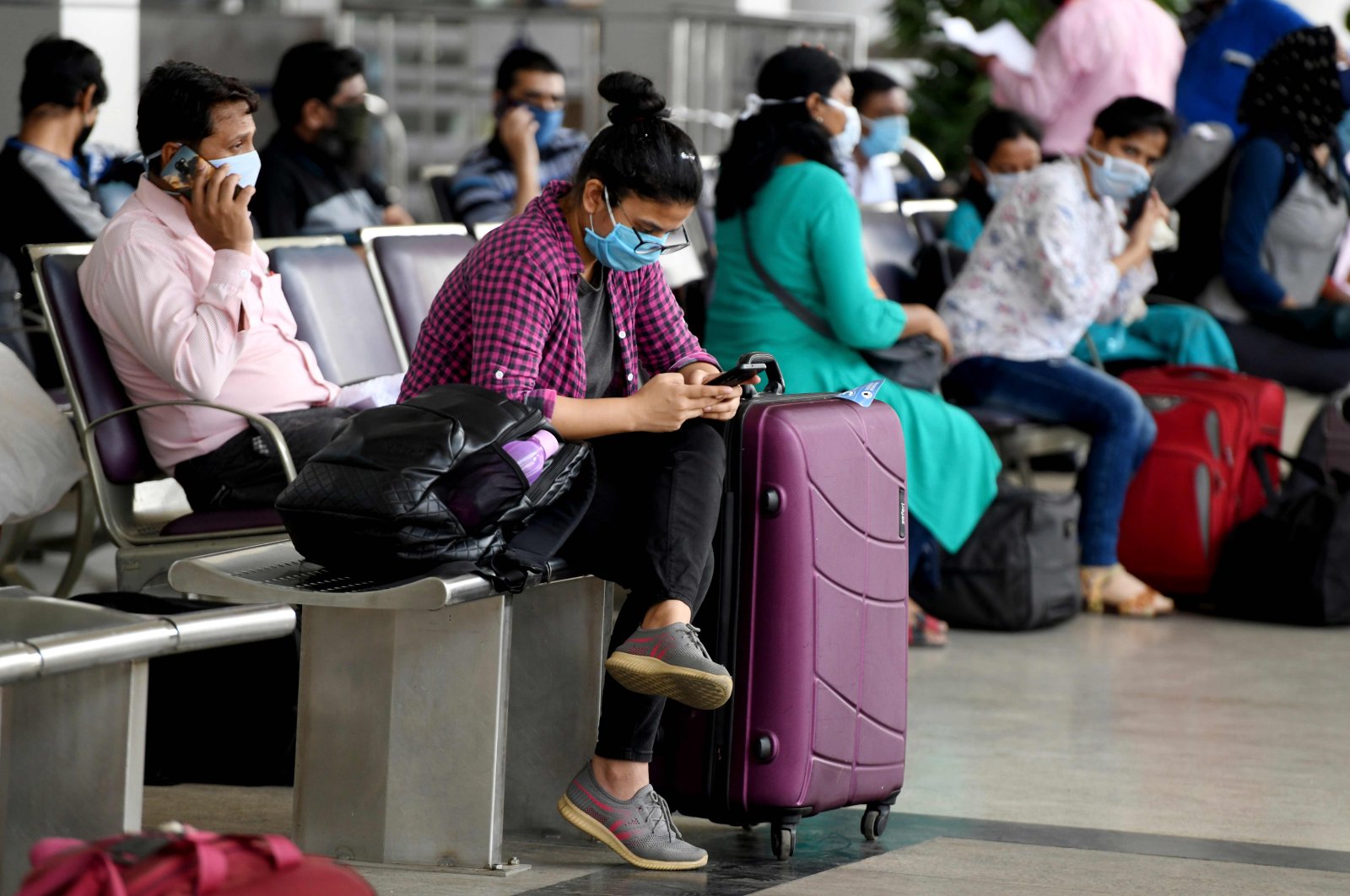 A passenger checks her mobile phone as she waits to check in at Kamaraj Domestic Airport during the first day of the resumption of domestic flights after the government imposed a nationwide lockdown as a preventive measure against the spread of the coronavirus, Chennai, May 25, 2020. (AFP Photo)