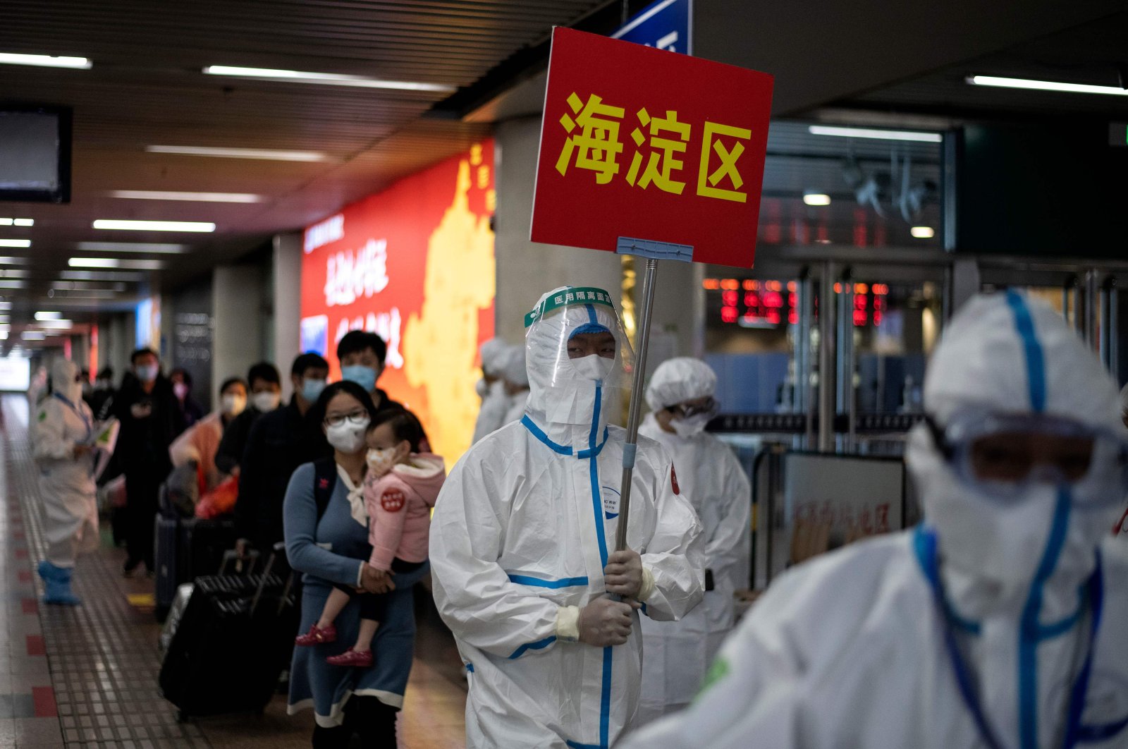 Transport personnel wearing hazmat suits guide travelers arriving from Wuhan to buses, which will take them to their quarantine locations, at Beijing West Railway Station, April 15, 2020. (AFP Photo)
