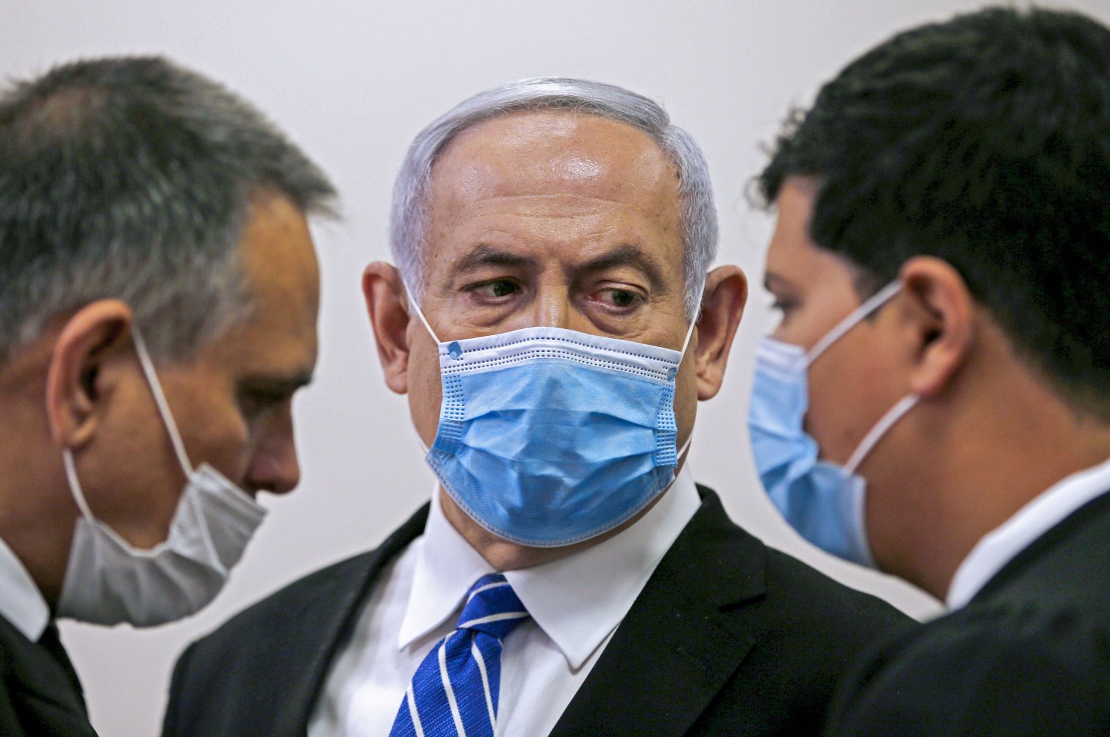 Israeli Prime Minister Benjamin Netanyahu (C), wearing a protective face mask, speaks with his lawyer inside a courtroom during the first day of his corruption trial, Jerusalem, May 24, 2020.  (AFP Photo)