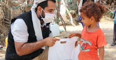 A TIKA worker hands an aid package to a girl in Yemen, May 21, 2020. (AA Photo)