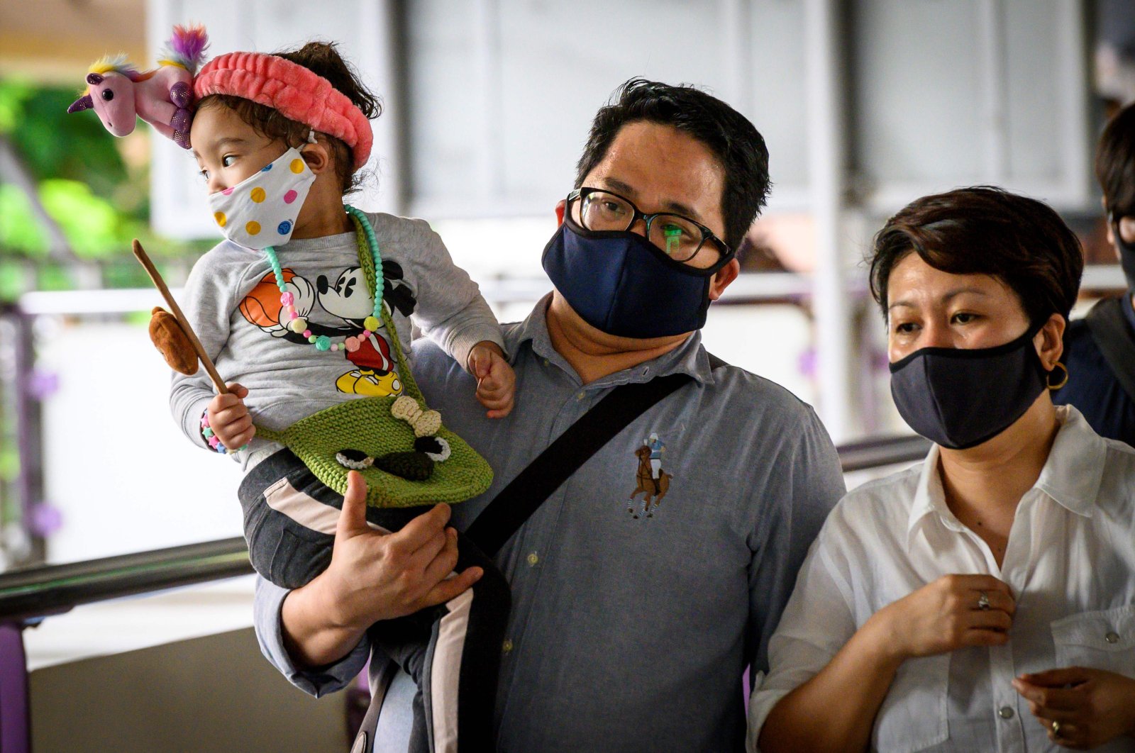 A child wearing a face mask is carried into a train station at rush hour in Bangkok, Thailand, as Thais continued their return to work following the lifting of restrictions to halt the spread of the coronavirus, May 25, 2020. (AFP Photo)