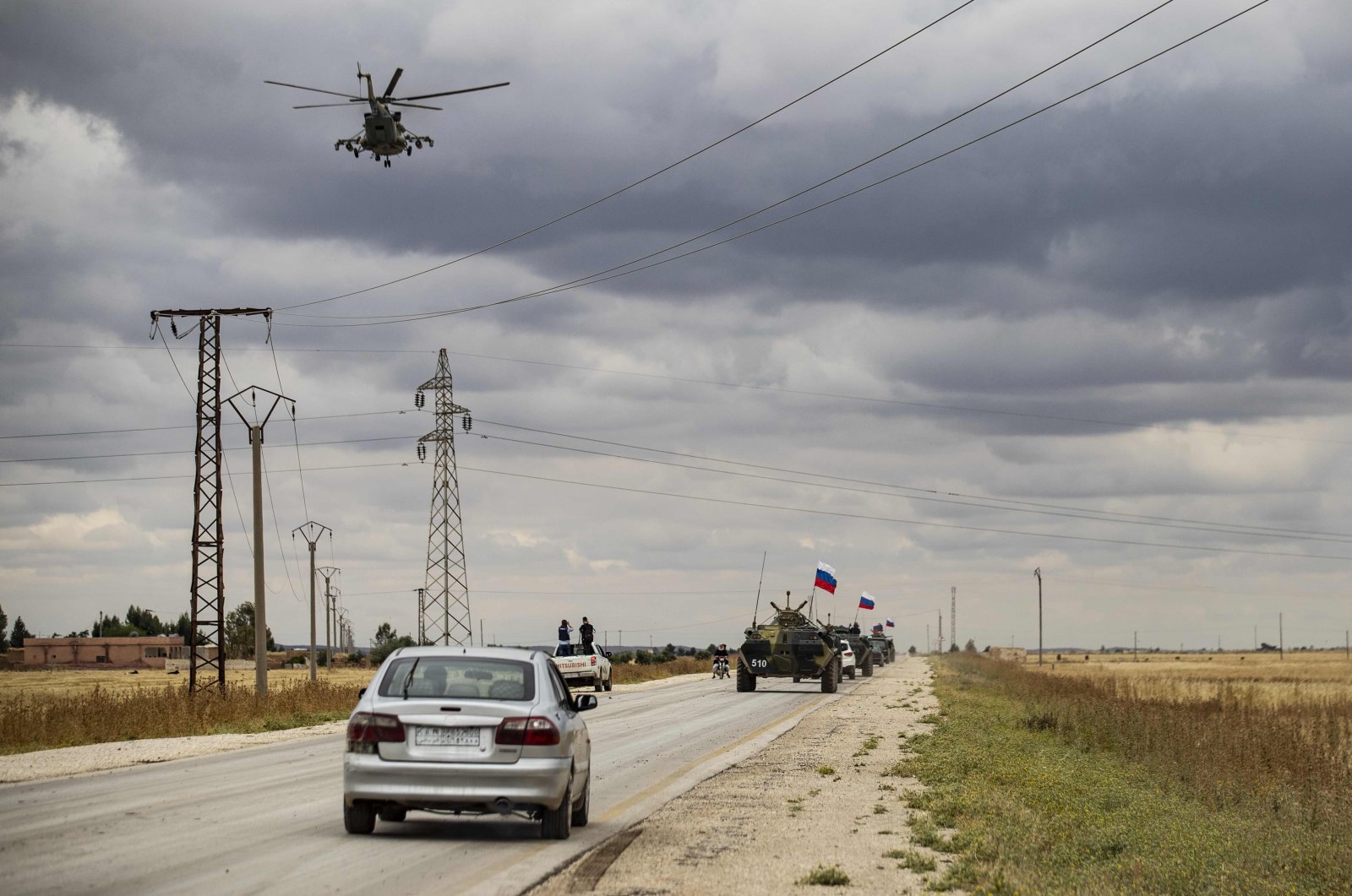 A Russian military helicopter accompanies military and civilian vehicles along the M4 highway by the town of Tal Tamr on May 25, 2020. (AFP Photo)