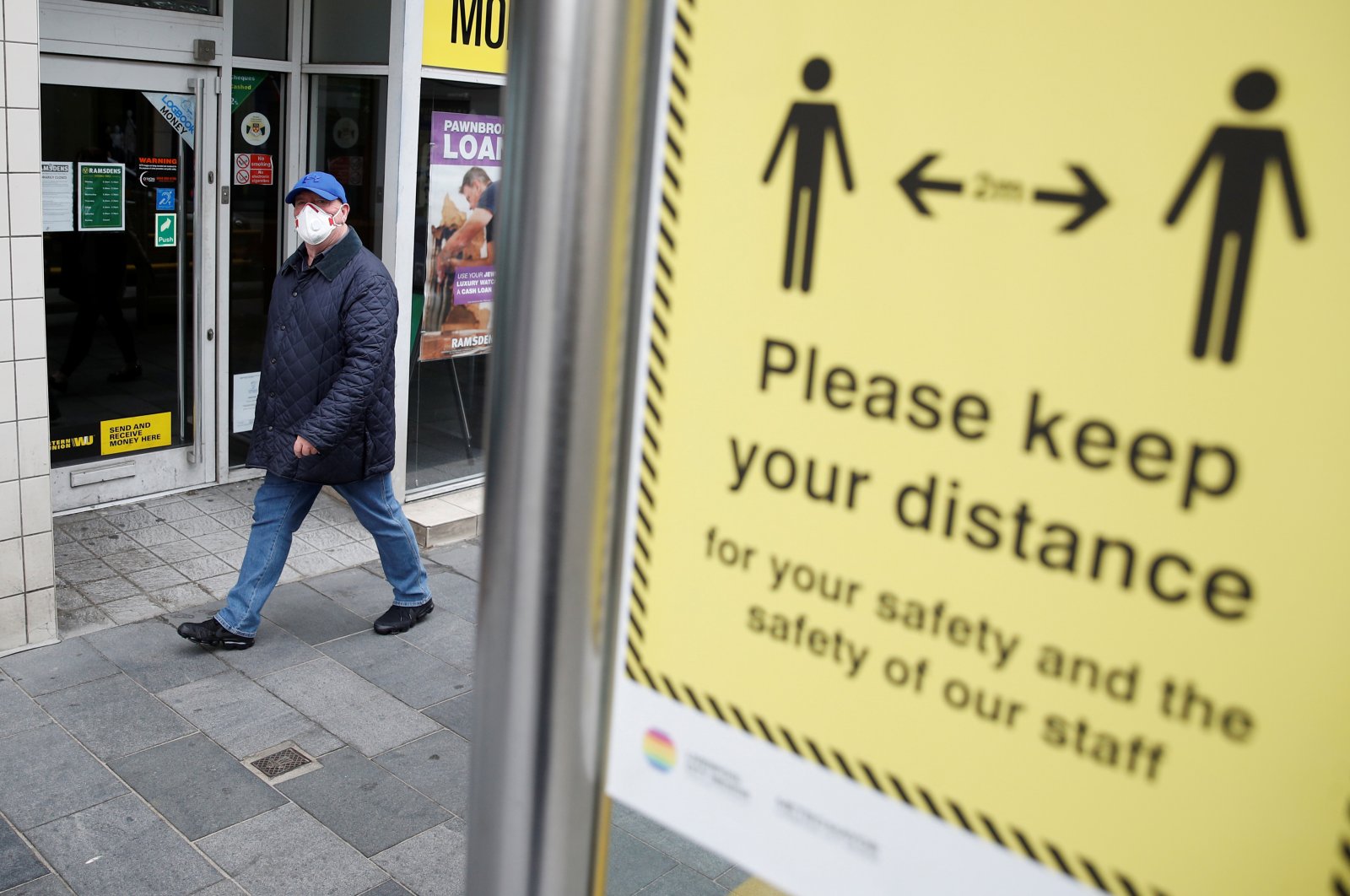 A man wearing a face mask walks by a social distance sign in Liverpool, following the outbreak of the coronavirus disease (COVID-19), Liverpool, Britain, May 26, 2020. (Reuters Photo) 