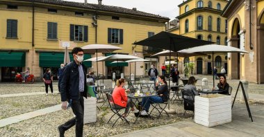 Residents have a drink at a cafe terrace and go about their activities in central Codogno, southeast of Milan, one of the villages at the epicenter of the coronavirus pandemic, Italy, May 20, 2020. (AFP Photo)