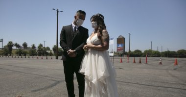 Roselle Querido, right, and her bridegroom Mo de las Alas wait for their marriage service to begin in the parking lot of the Honda Center in Anaheim, Calif., Tuesday, May 26, 2020. (AP Photo)