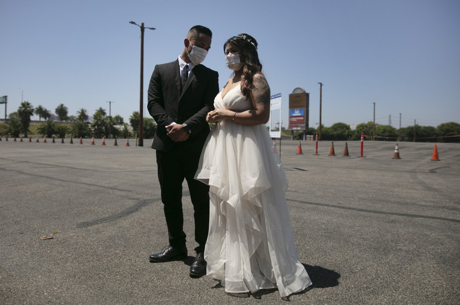 Roselle Querido, right, and her bridegroom Mo de las Alas wait for their marriage service to begin in the parking lot of the Honda Center in Anaheim, Calif., Tuesday, May 26, 2020. (AP Photo)