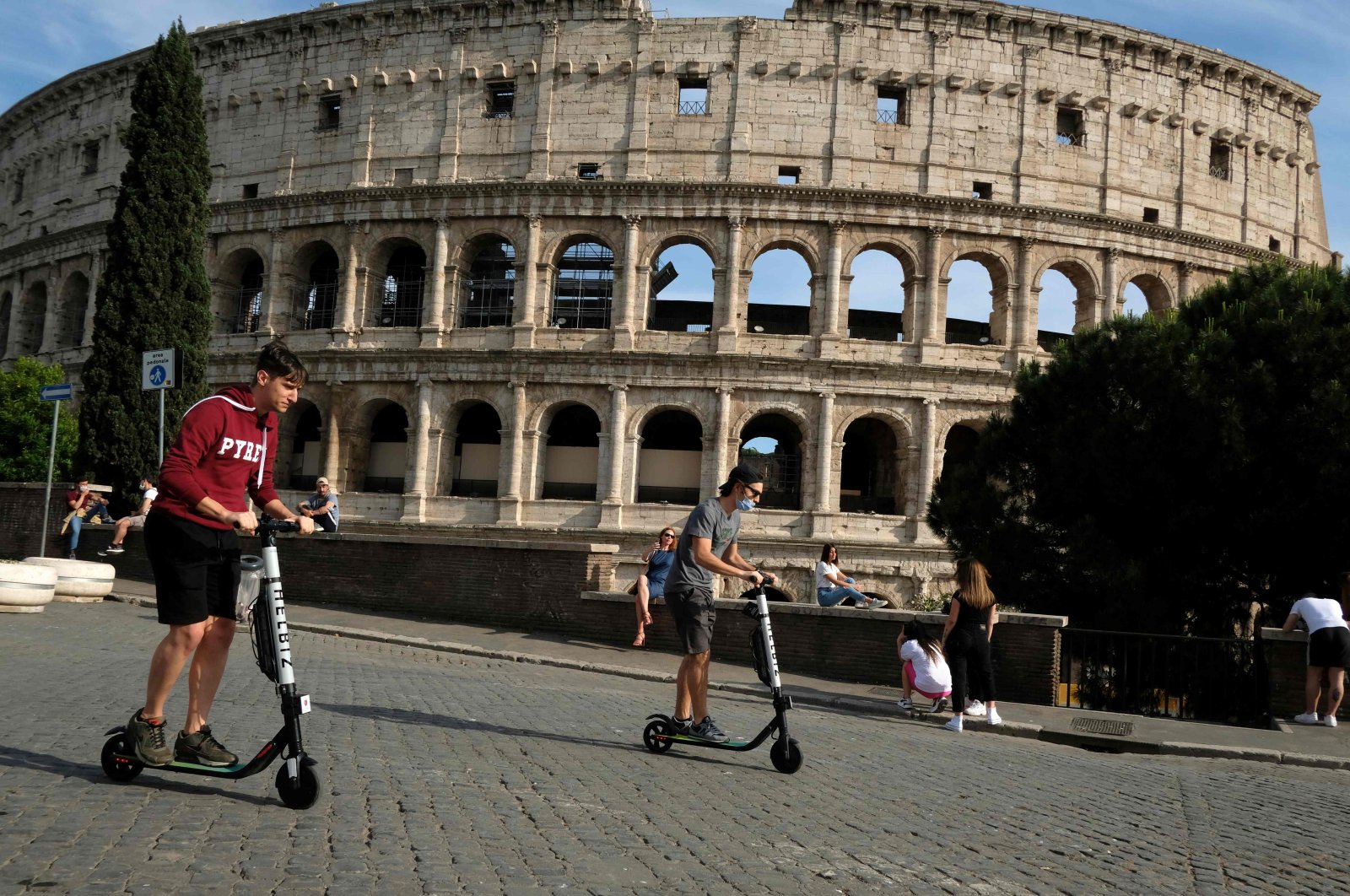 People ride electric scooters, past the Colosseum monument, Rome, May 28, 2020. (AFP Photo)