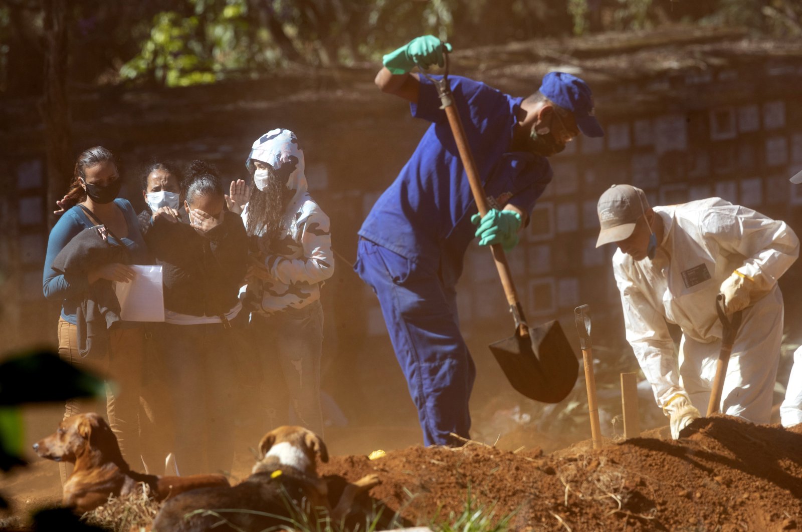 Relatives mourn as they watch cemetery workers shovel dirt over a coffin, at the Vila Formosa cemetery in Sao Paulo, Brazil, Thursday, May 28, 2020. (AP Photo/Andre Penner)