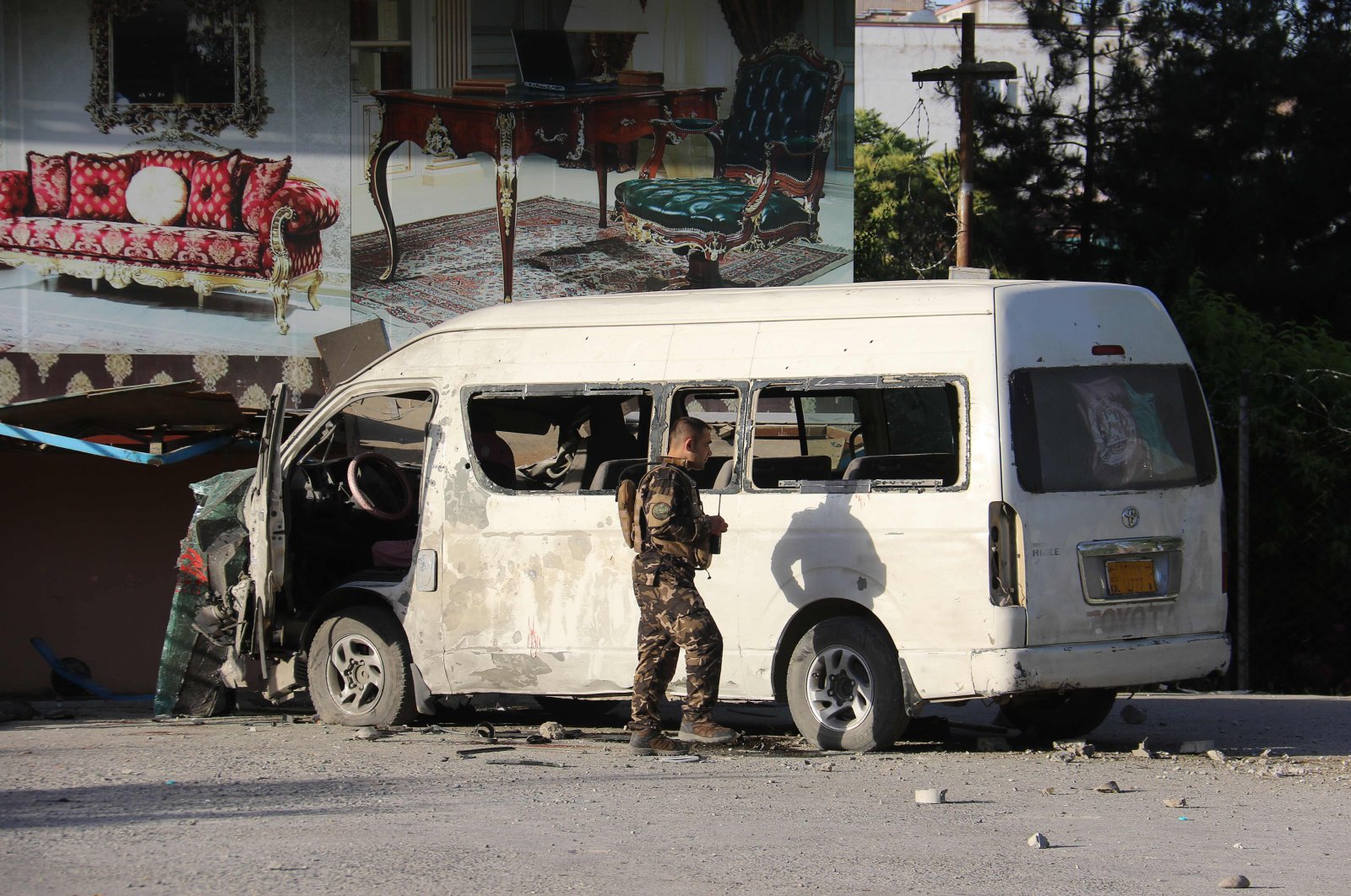 An Afghan security personnel investigates a damaged vehicle carrying employees of Khurshid TV along a roadside, at the site of a bomb blast in Kabul on May 30,2020. (AFP Photo)