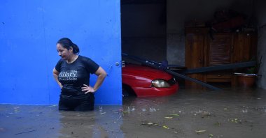 A woman is seen with floodwaters up to her hips as she stands outside her house in the flooded Santa Lucia colony in Ilopango, El Salvador, during Tropical Storm Amanda, May 31, 2020. (AFP Photo)