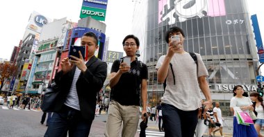 Men play the augmented reality mobile game "Pokemon Go" by Nintendo on their mobile phone as they walk at a busy crossing in Shibuya district in Tokyo, Japan, July 22, 2016. (Reuters File Photo)
