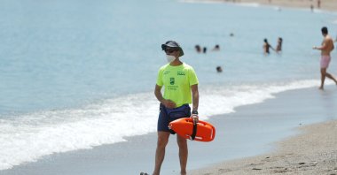 A lifeguard wears a protective face mask as he keeps watch at the shore on La Malagueta beach, Malaga, southern Spain, June 1, 2020. (Reuters Photo)