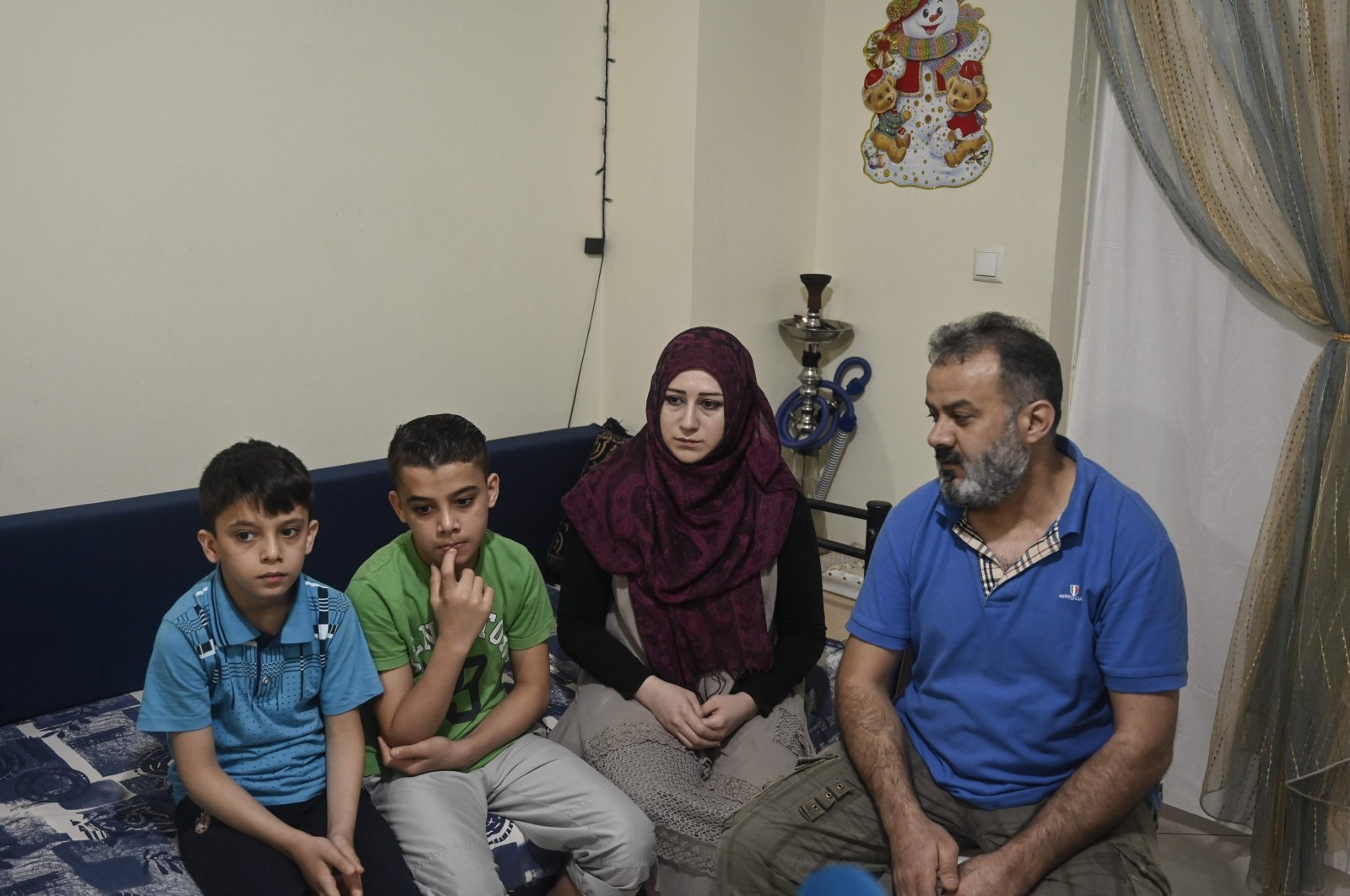 Abdelkader Rahmoun (R), a 44-year-old Syrian and his family sit in their apartment provided by NGO's through EU programs, at a working-class district in Piraeus near Athens on May 29, 2020. (AFP Photo)