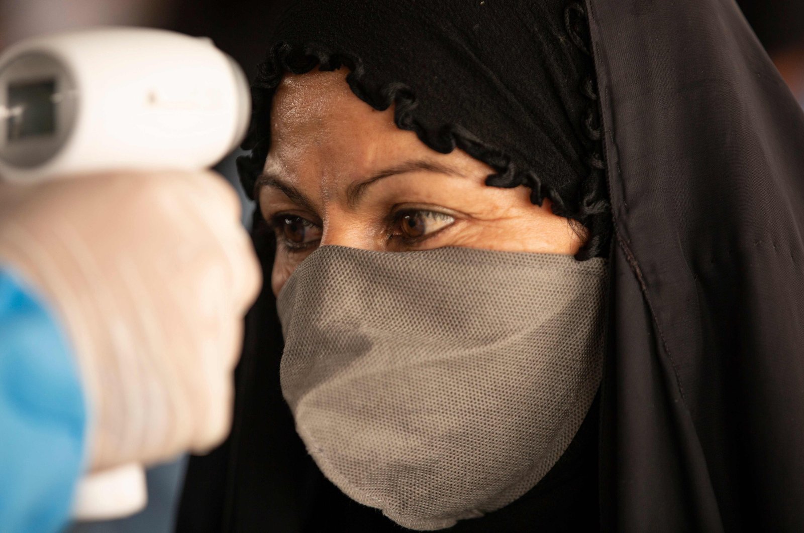 An Iraqi woman who had been stranded in Iran due to the coronavirus pandemic, gets her temperature checked by a health worker upon her arrival to Iraq via the Al-Shalamija border crossing, west of the southern city of Basra, Iraq, May 27, 2020. (AFP Photo)