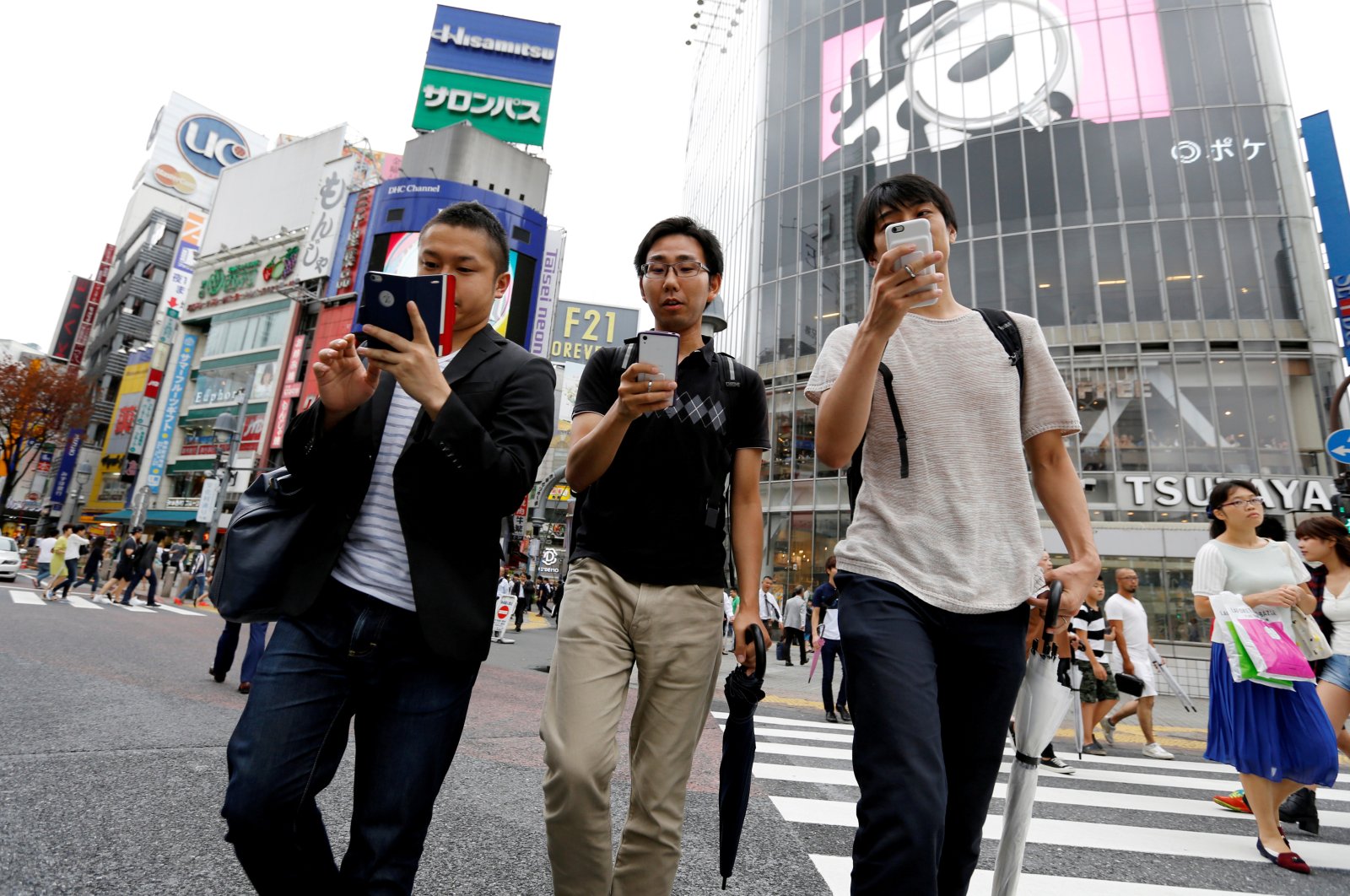 Men play the augmented reality mobile game "Pokemon Go" by Nintendo on their mobile phone as they walk at a busy crossing in Shibuya district in Tokyo, Japan, July 22, 2016. (Reuters File Photo)
