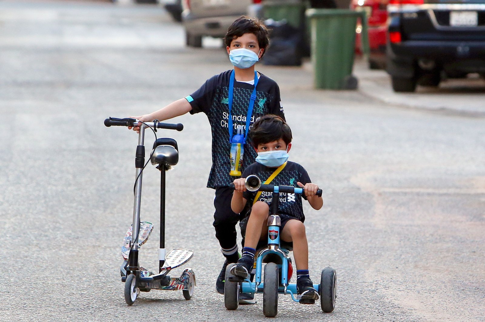 Kuwaiti children, wearing protective facemasks, cycle in a street in the Salwa district of Kuwait City, May 29, 2020. (AFP Photo)