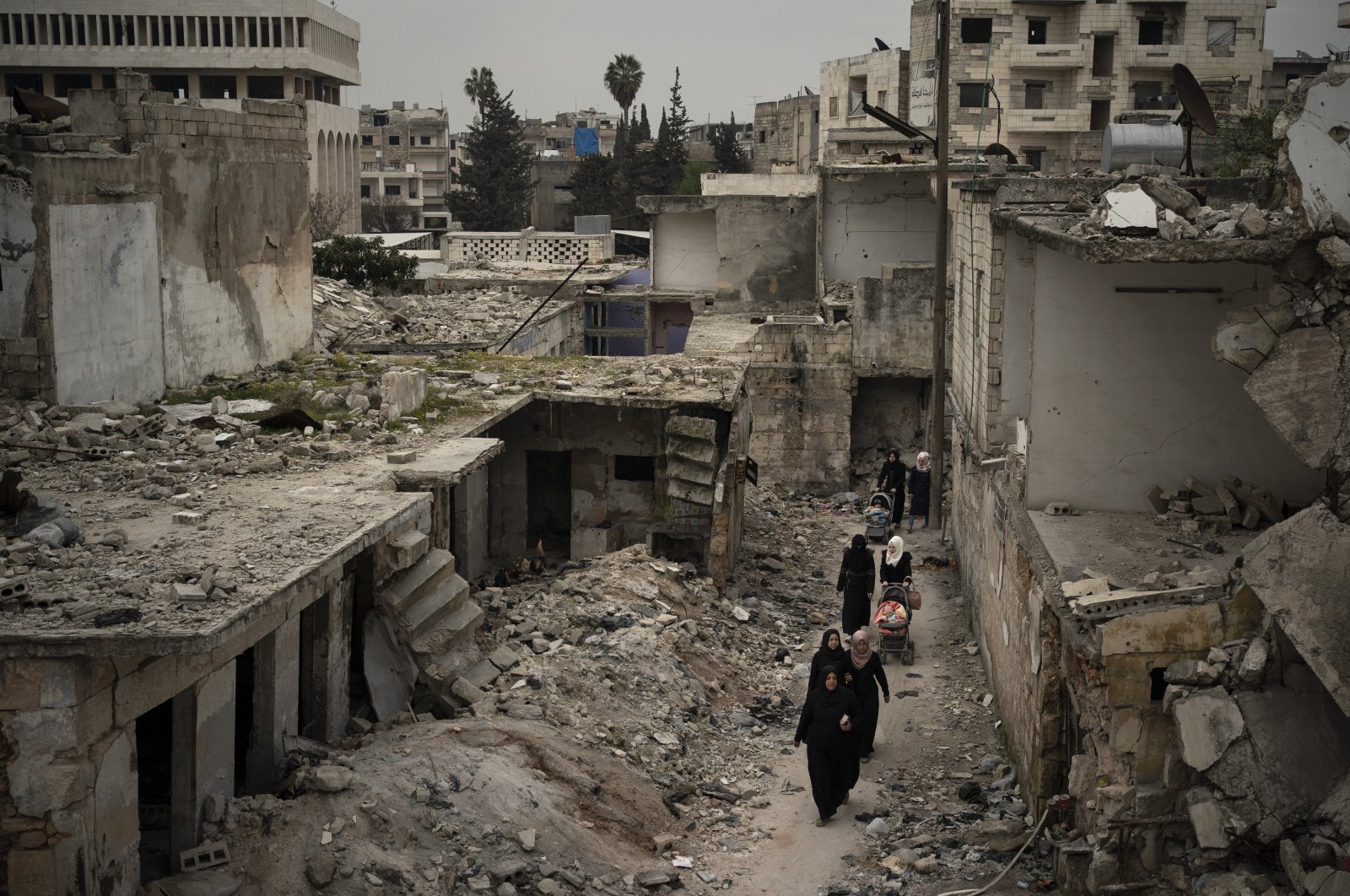 Women walk in a neighborhood heavily damaged by airstrikes in Idlib, Syria, March 12, 2020. (AP)