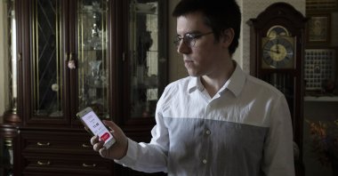 Vladimir Perevalov shows a Social Monitoring app installed on his phone in his apartment in Shcherbinka, outside Moscow, Russia, May 27, 2020. (AP Photo)