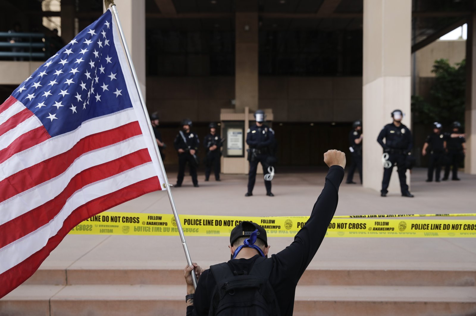 A demonstrator holds up his fist while kneeling before police officers during a protest over the death of George Floyd, Anaheim, Calif., June 1, 2020. (AP Photo)