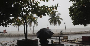A man sits on a bench as it rains by the shores of the Arabian Sea in Mumbai, India, June 3, 2020. (AP Photo)