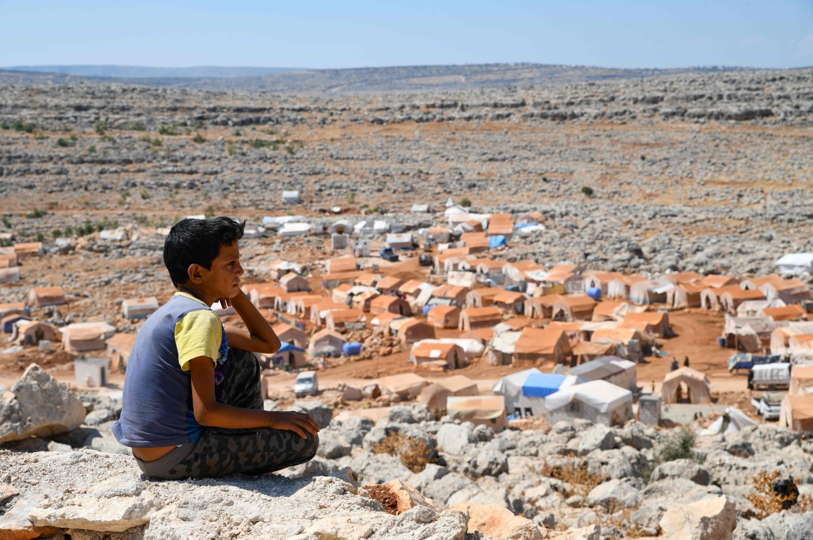 A young Syrian boy who was displaced from the town of Khan Sheikhoun gazes from a small hilltop at the makeshift camp where he currently lives, in the northern countryside of Idlib province near the Turkish border, Sept. 8, 2019. (AFP Photo)