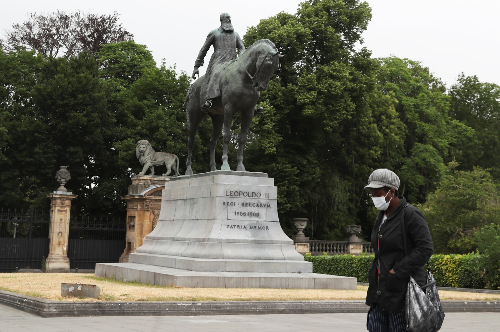A person wearing a protective face mask walks past the statue of Belgian King Leopold II, near Brussels' Royal Palace, in Brussels, Belgium, June 4, 2020. (Reuters Photo)