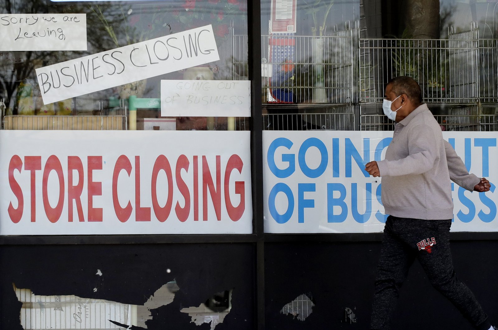A man walks past signs of a store going out of business during the coronavirus outbreak in Niles, Illinois, U.S., May 21, 2020. (AP Photo)