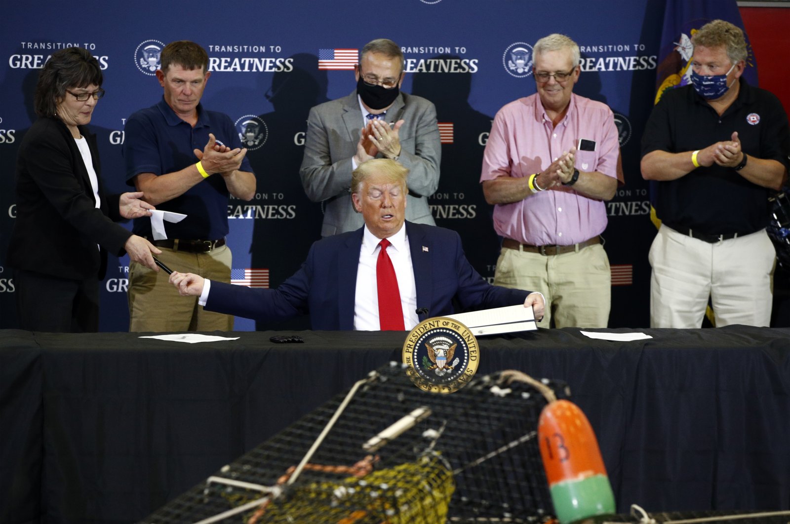 President Donald Trump hands pens out after signing an executive order on commercial fishing after speaking at a roundtable discussion with commercial fishermen at Bangor International Airport in Bangor, Maine, June 5, 2020. (AP Photo)