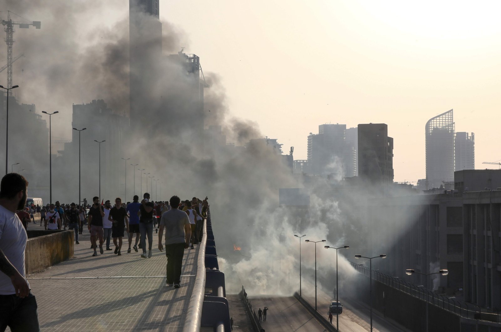 Lebanese protesters walk away from tear gas fired by riot police amid clashes following a demonstration in central Beirut on June 6, 2020. (AFP Photo)