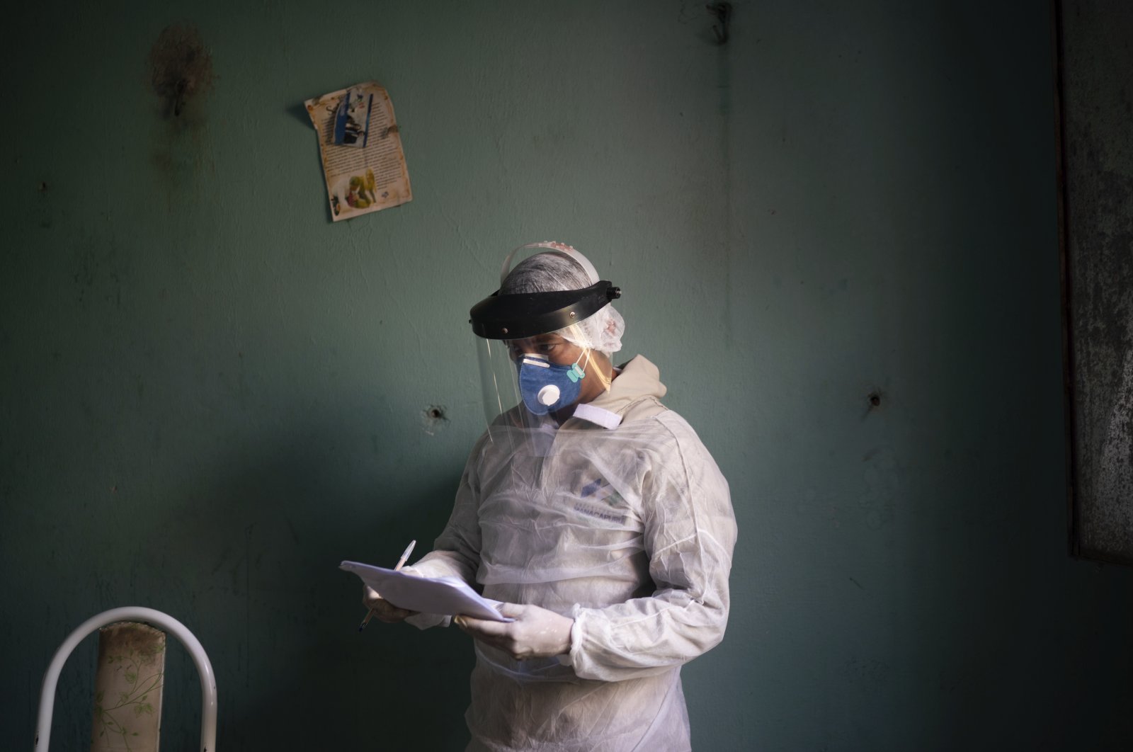 A health worker takes notes as he prepares to collect material for a COVID-19 test on an elderly woman, Manacapuru, Brazil, June 3, 2020. (AP Photo)