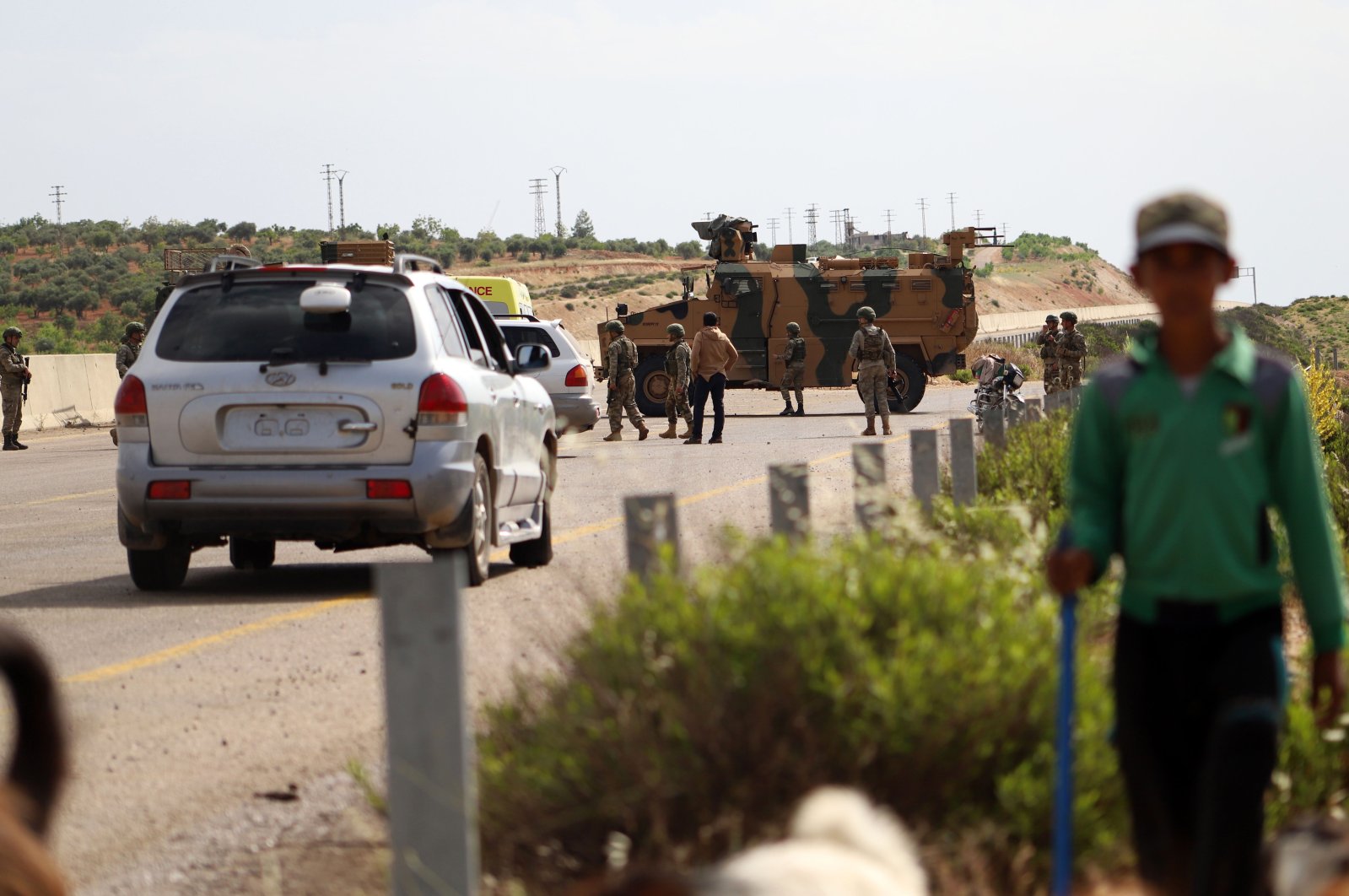 A shepherd boy leads his flock near Turkish soldiers standing outside an armored vehicle, part of a joint Turkish-Russian military patrol, along the M4 highway in Ariha in the opposition-held northwestern Syrian province of Idlib, June 2, 2020. (AFP Photo)
